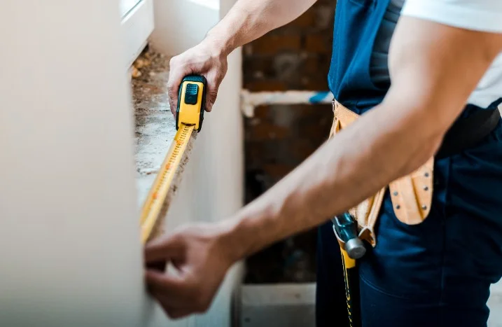 Person misst Fensternische mit Zollstock aus